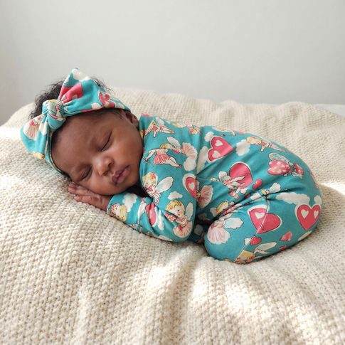 New baby girl wearing cherubs print babygrow with matching bow headband