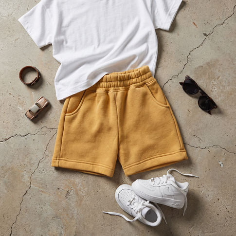 Ochre sweat toddler shorts flat lay image with white tshirt and trainers