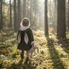 Little girl wearing Lottie & Lysh bunny jacket, carrying a bunny toy, in a woodland scene.