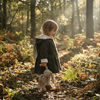Little girl wearing a bunny jacket walking through the woods. Carrying a very loved toy rabbit.