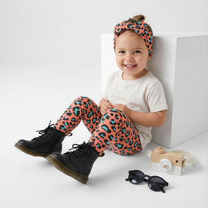 Toddler girl wearing Lottie & Lysh coral leopard print leggings with matching headband, white t-shirt and Dr Martens Boots.