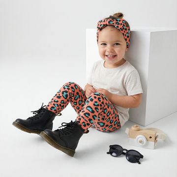 Toddler girl wearing Lottie & Lysh coral leopard print leggings with matching headband, white t-shirt and Dr Martens Boots.