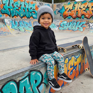 Child sitting on a graffiti-covered wall with a skateboard