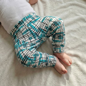 Baby wearing blue and black patterned leggings on a light gray blanket