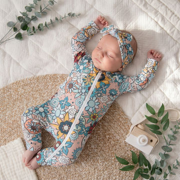 Sleeping baby girl wearing Lottie & Lysh Zipped sleepsuit with retro floral design, and matching headband.