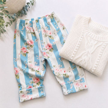 Floral striped pants with a white knit sweater on a light background