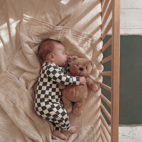Sleeping baby boy with teddy bear. Wearing forest checkerboard romper by Lottie & Lysh