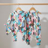Colorful baby romper with abstract patterns on hangers against a neutral background