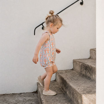 toddler girl walking up steps wearing a lobster print summer romper