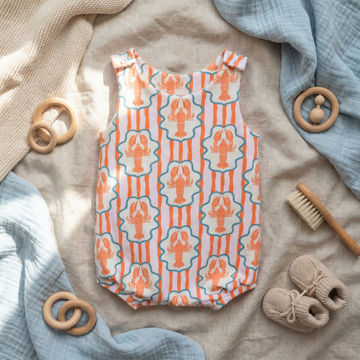 Baby romper with lobster pattern on a textured surface with toys and baby items.