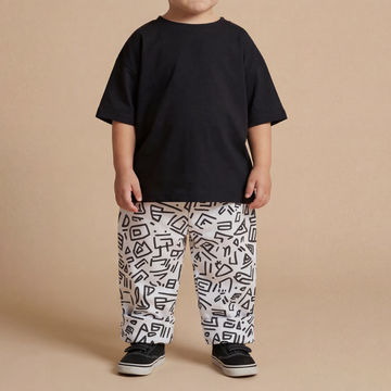 Toddle wearing a black oversized t-shirt with white and black printed baggy trousers