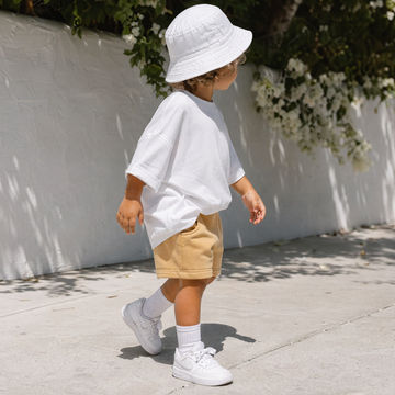 ochre sweat toddler shorts styled with white oversized t-shirt, trainers and sun hat
