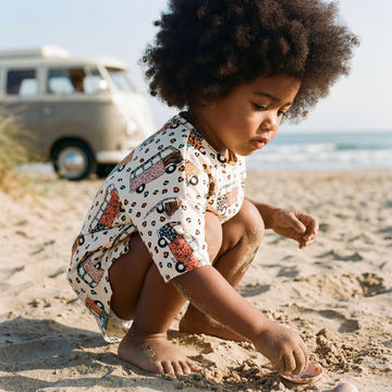 Toddler playing on the beach wearing a campervan print t-shirt summer dress