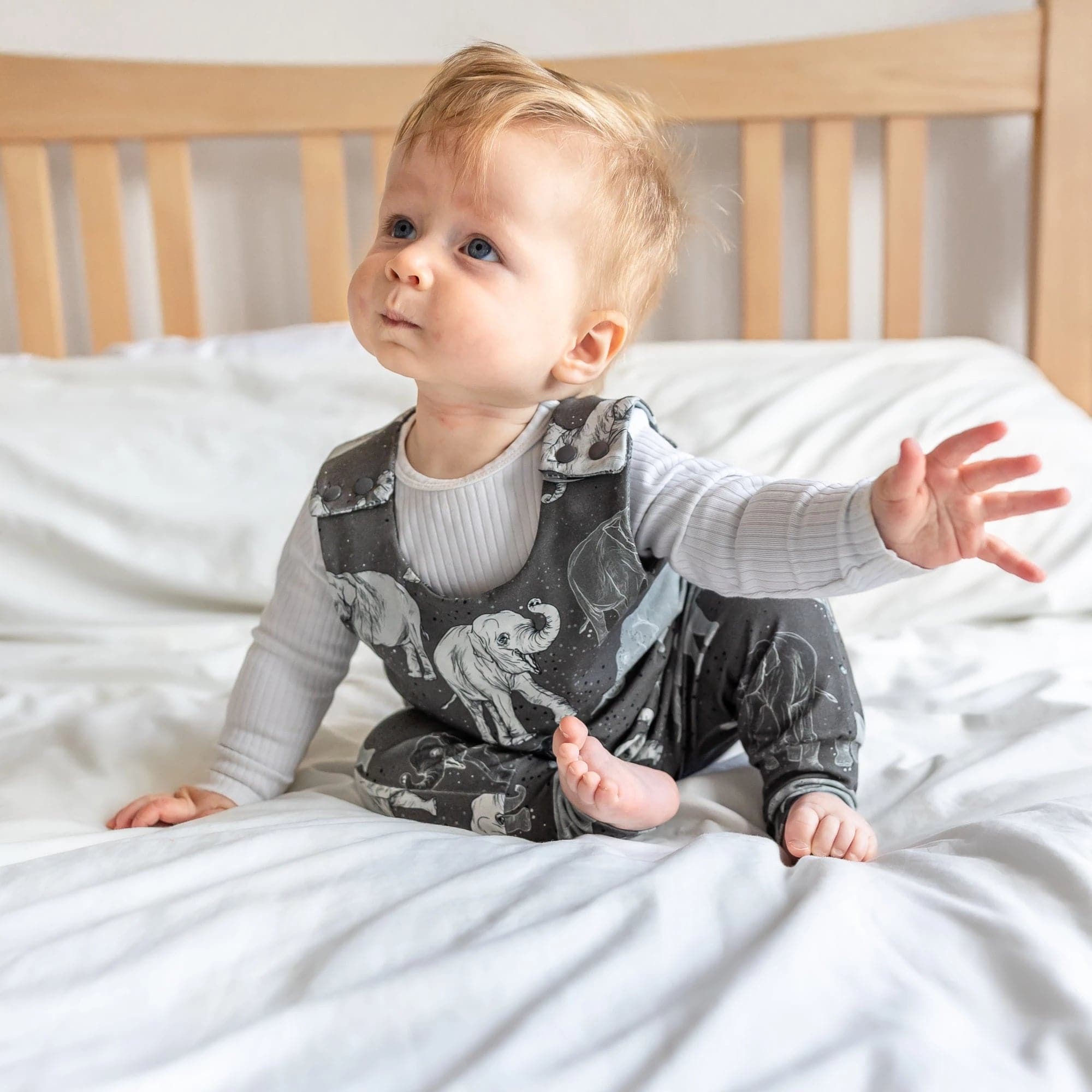 cute baby boy wearing Lottie & Lysh elephant printed dungarees whilst smiling at the camera
