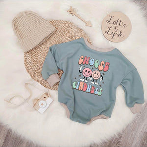 Green Printed sweater romper handmade in the UK. 'Choose kindness' print detail. Photographed alongside a beige knitted beanie hat.