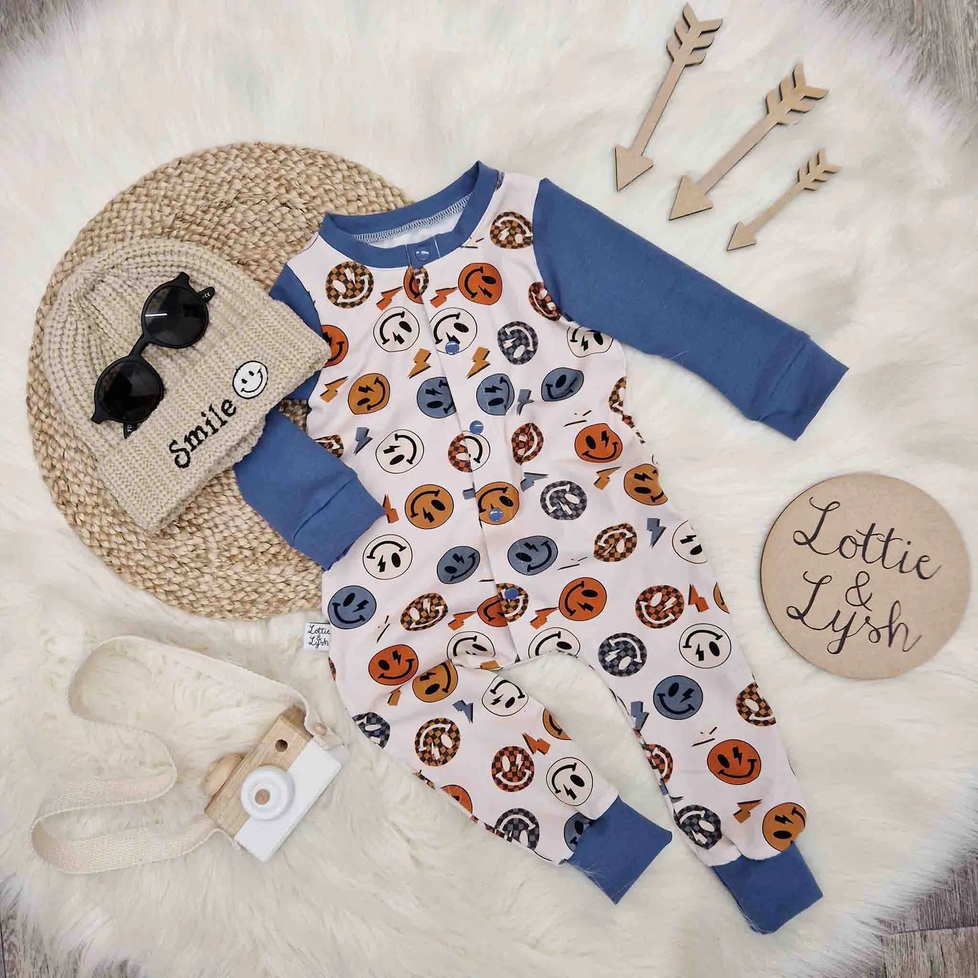 Lottie & Lysh flat lay image featuring the vintage smiling face romper, smile beanie hat and accessories