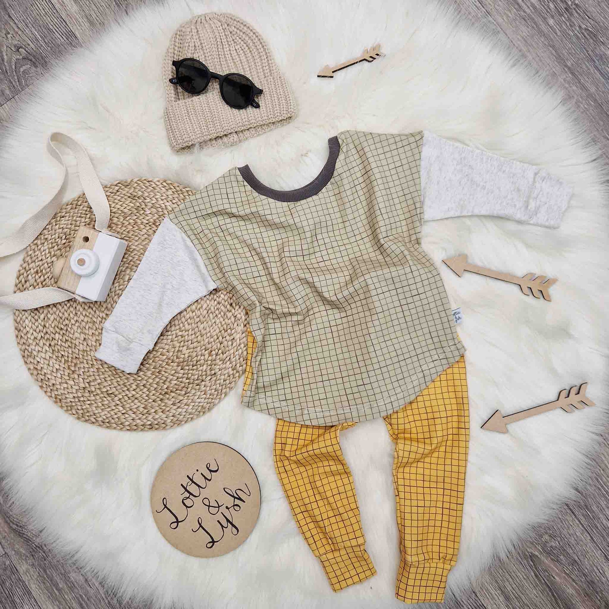 kids outfit flat lay image featuring L&L mustard grid leggings, sage green grid top, beige knitted beanie hat and black sunglasses