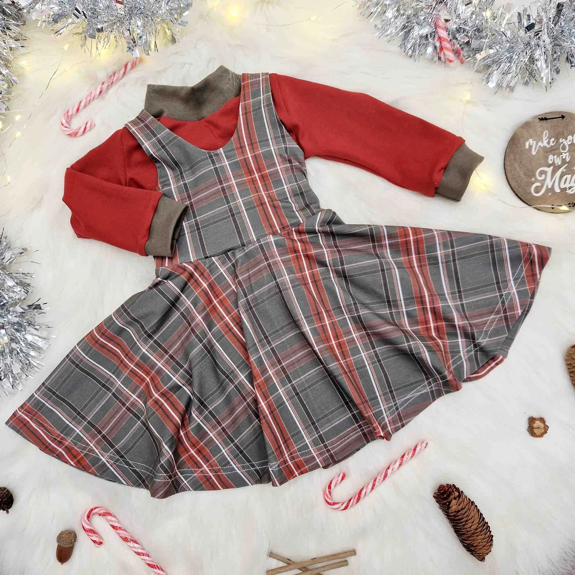 Baby girl's Christmas flatlay featuring a green tartan dress and matching red top