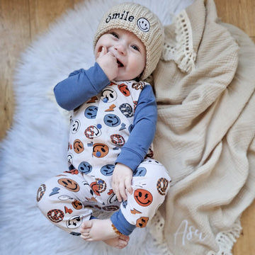 Baby boy wearing smile face babygrow and knitted beanie hat made by Lottie & Lysh