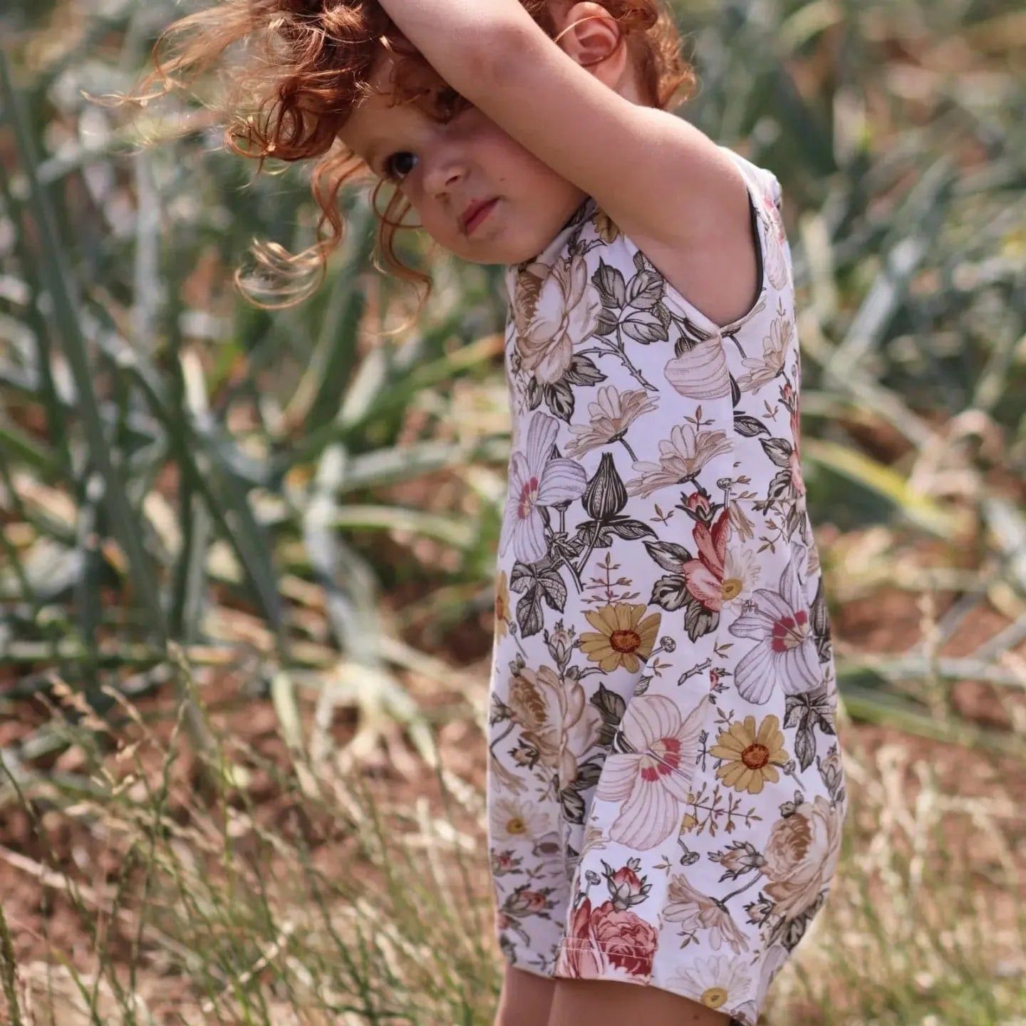 little girl wearing a floral short playsuit made by Lottie & Lysh