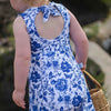 A photo showing the back of the Lottie & Lysh bow back romper. This little girl has blonde, curly hair and is wearing a blue and white floral playsuit. 