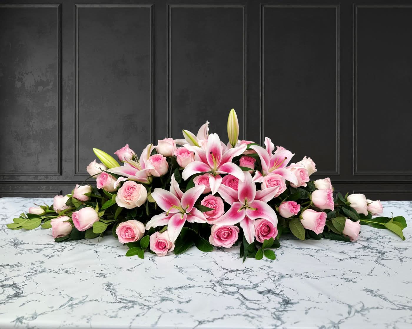 funeral spray of pink lilies and roses, funeral flowers and casket flowers in white
