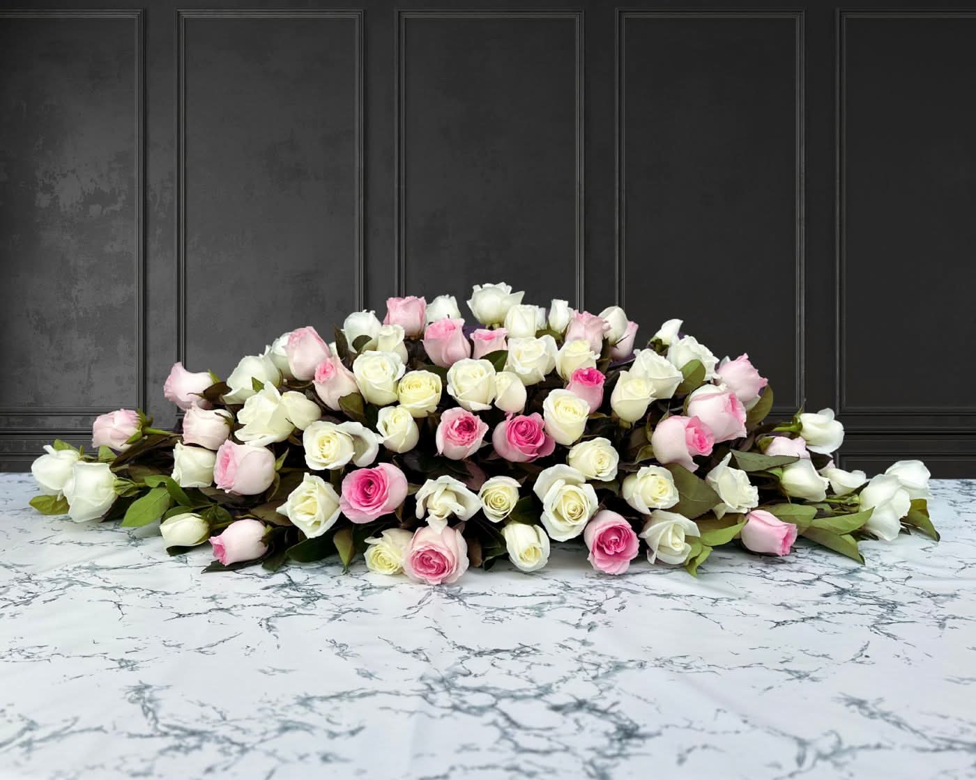 funeral spray of pink and white roses, funeral flowers and casket flowers in white