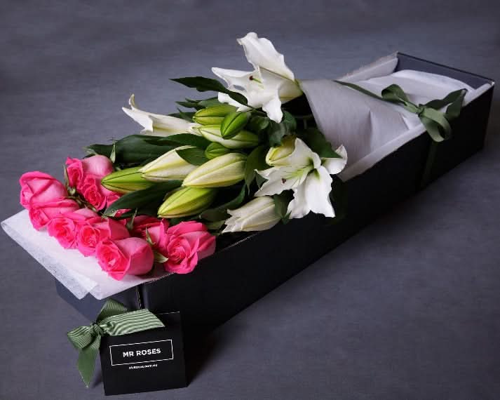 pink roses and white lilies flower arrangement in gift box
