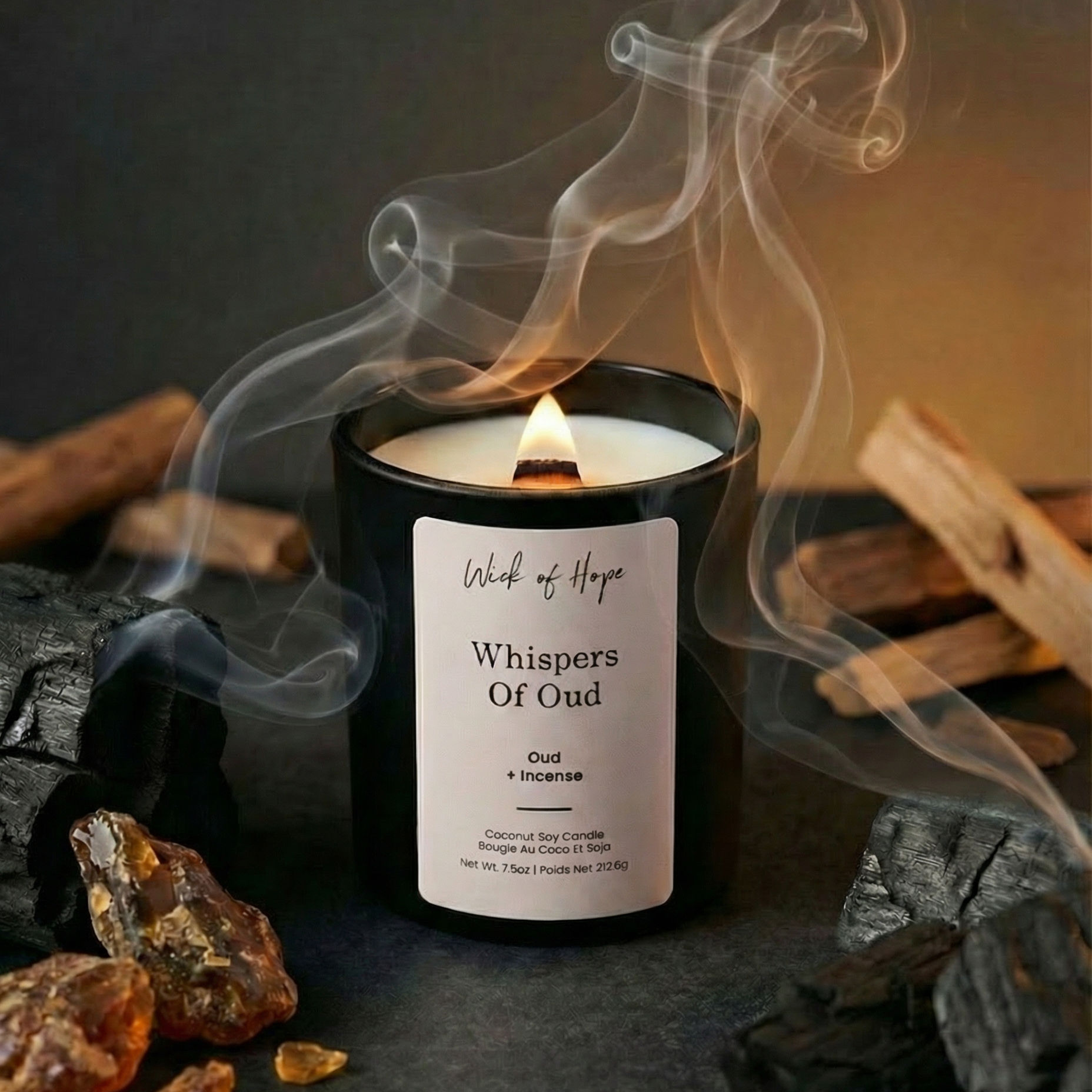 Candle labeled 'Whispers of Oud' with smoke and wooden elements on a dark background