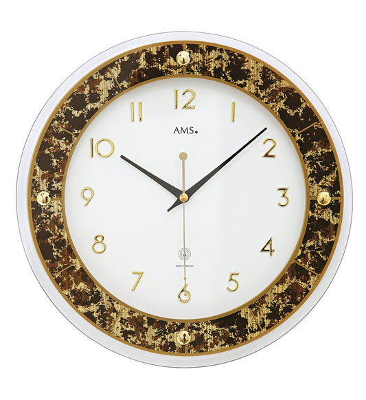Horloge murale marron avec anneau, chiffres et aiguilles dorés, logo AMS