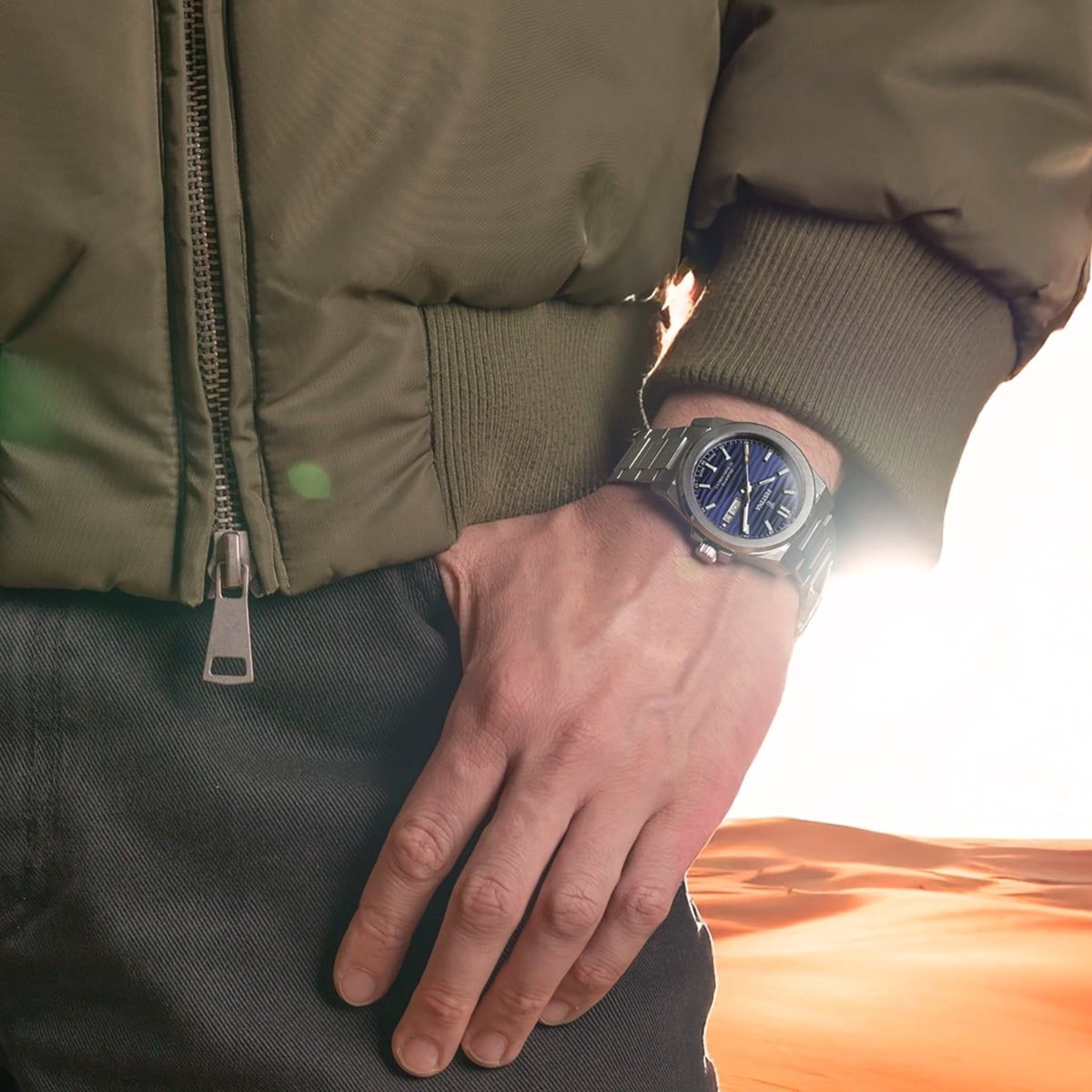 Herrenuhr am Handgelenk mit blauem Zifferblatt und Edelstahlarmband.