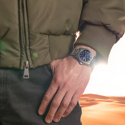 Herrenuhr am Handgelenk mit blauem Zifferblatt und Edelstahlarmband.