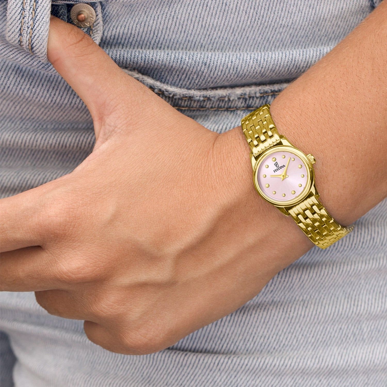 Damenarmbanduhr am Handgelenk: goldenes Metallarmband, rosafarbenes Zifferblatt mit Zeigern
