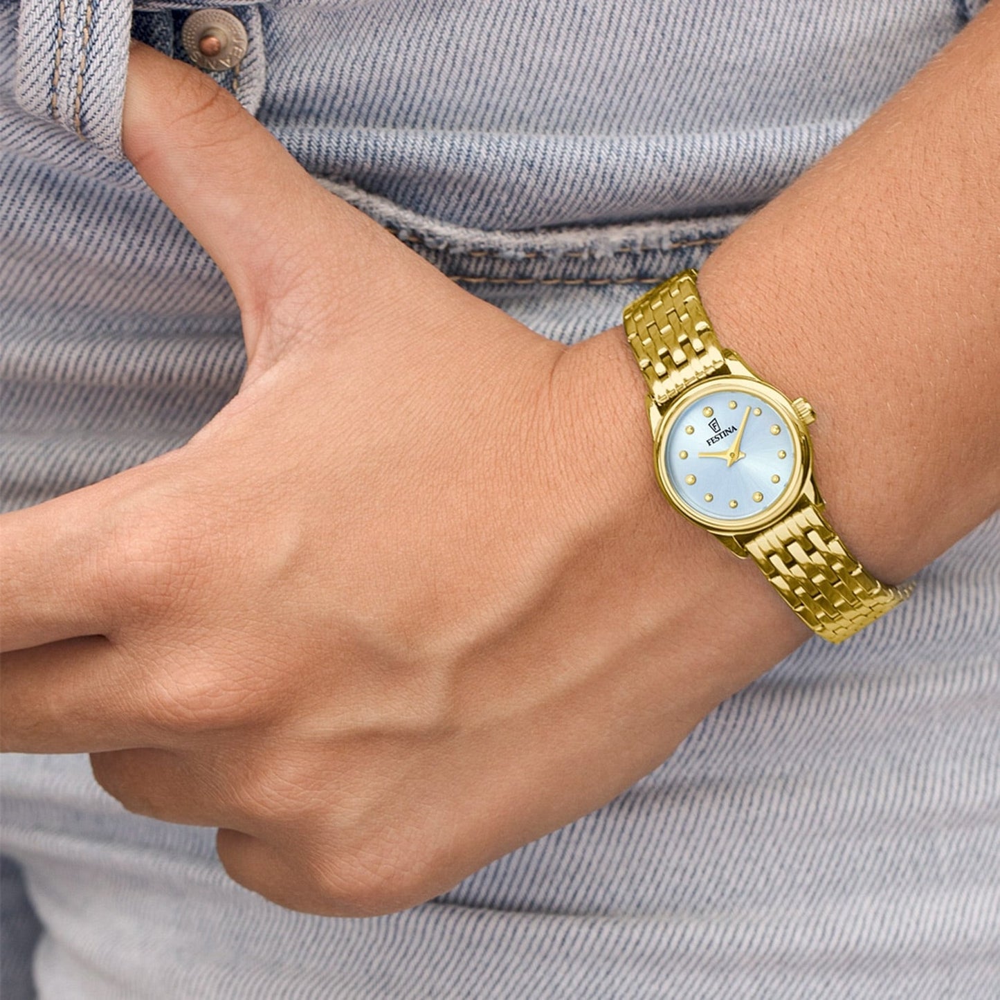 Damenuhr am Handgelenk mit goldenem Metallarmband und blauem Zifferblatt