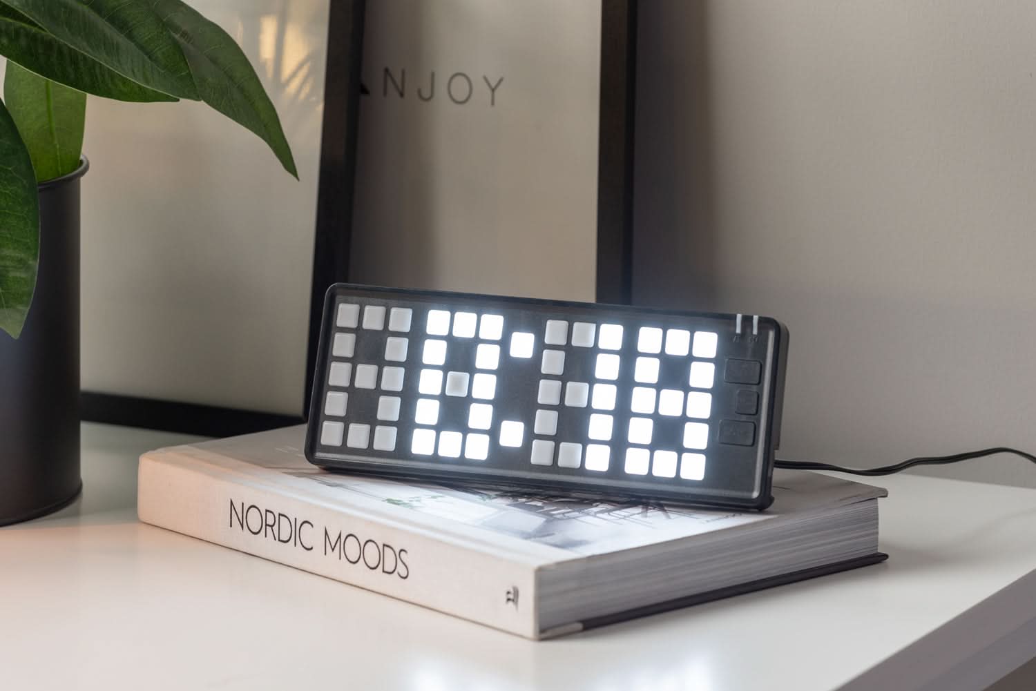 Réveil numérique avec clavier à touches lumineuses, placé sur une étagère