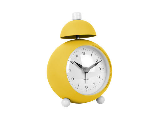 Réveil jaune pâle en forme de cloche, avec cadran rond et deux pieds.