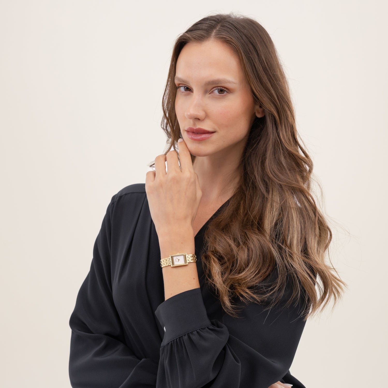 Goldfarbene Damenarmanduhr am Handgelenk mit Steinbesatz und Metallarmband