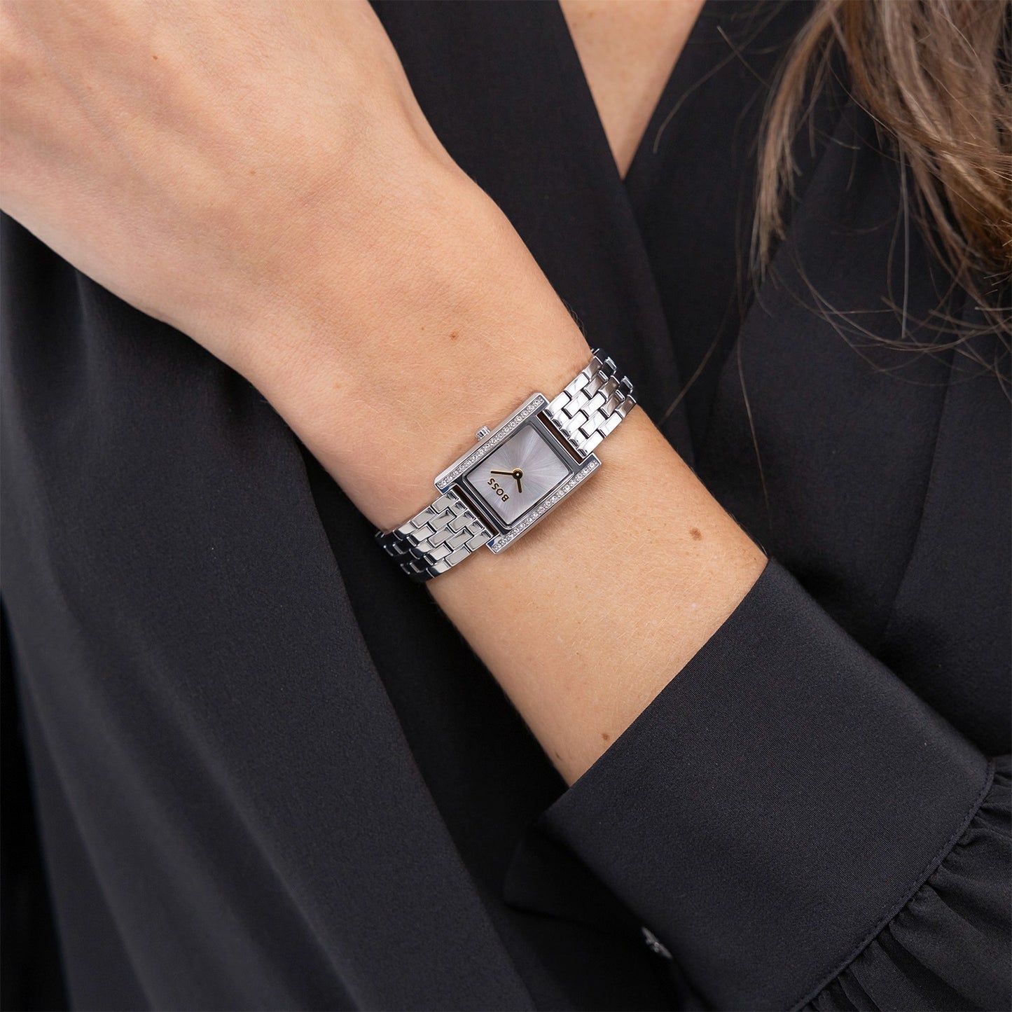 Armbanduhr am Handgelenk mit silberfarbenem Metallband und rechteckigem Zifferblatt