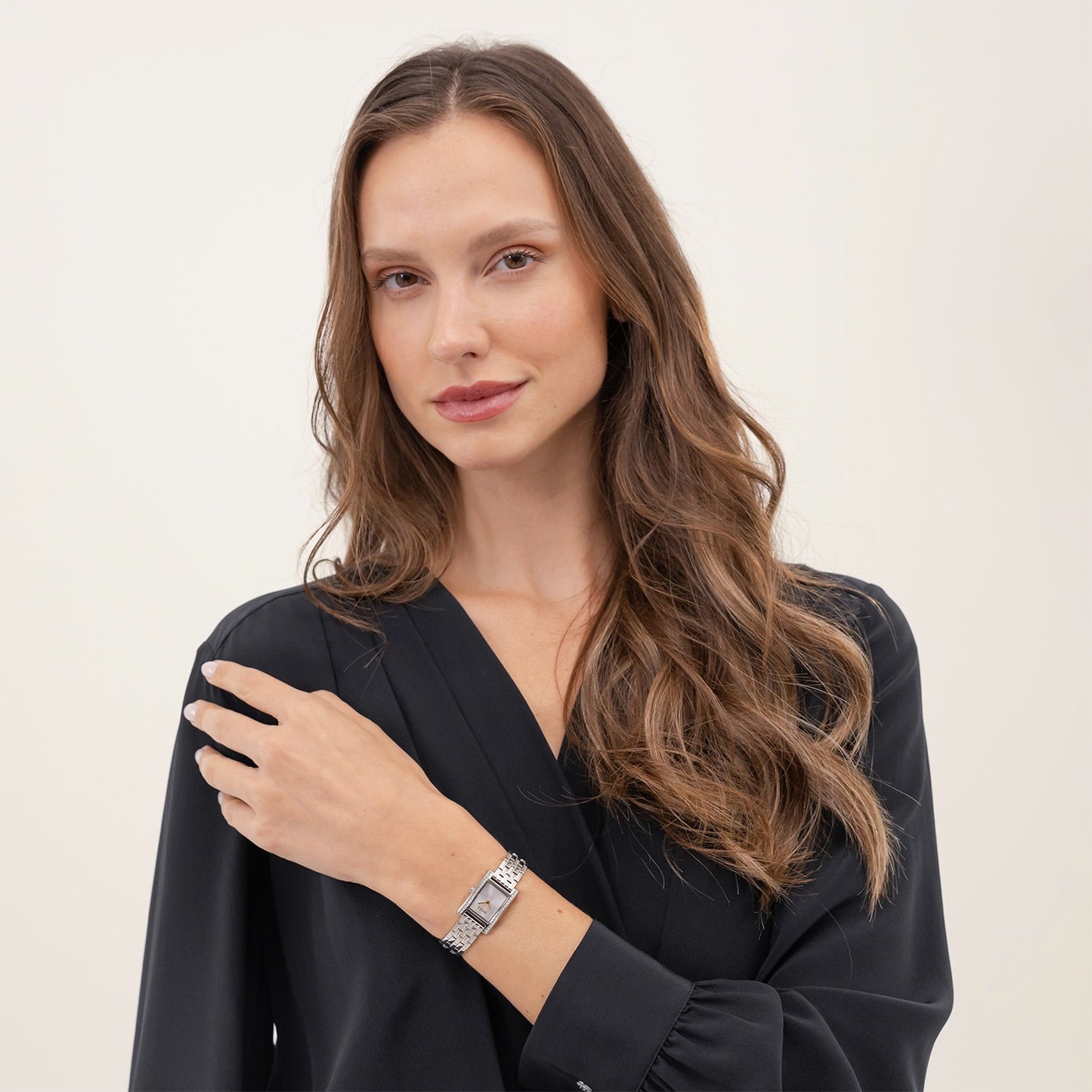 Damen-Armbanduhr am Handgelenk mit silberfarbenem Gliederarmband und rechteckigem Zifferblatt