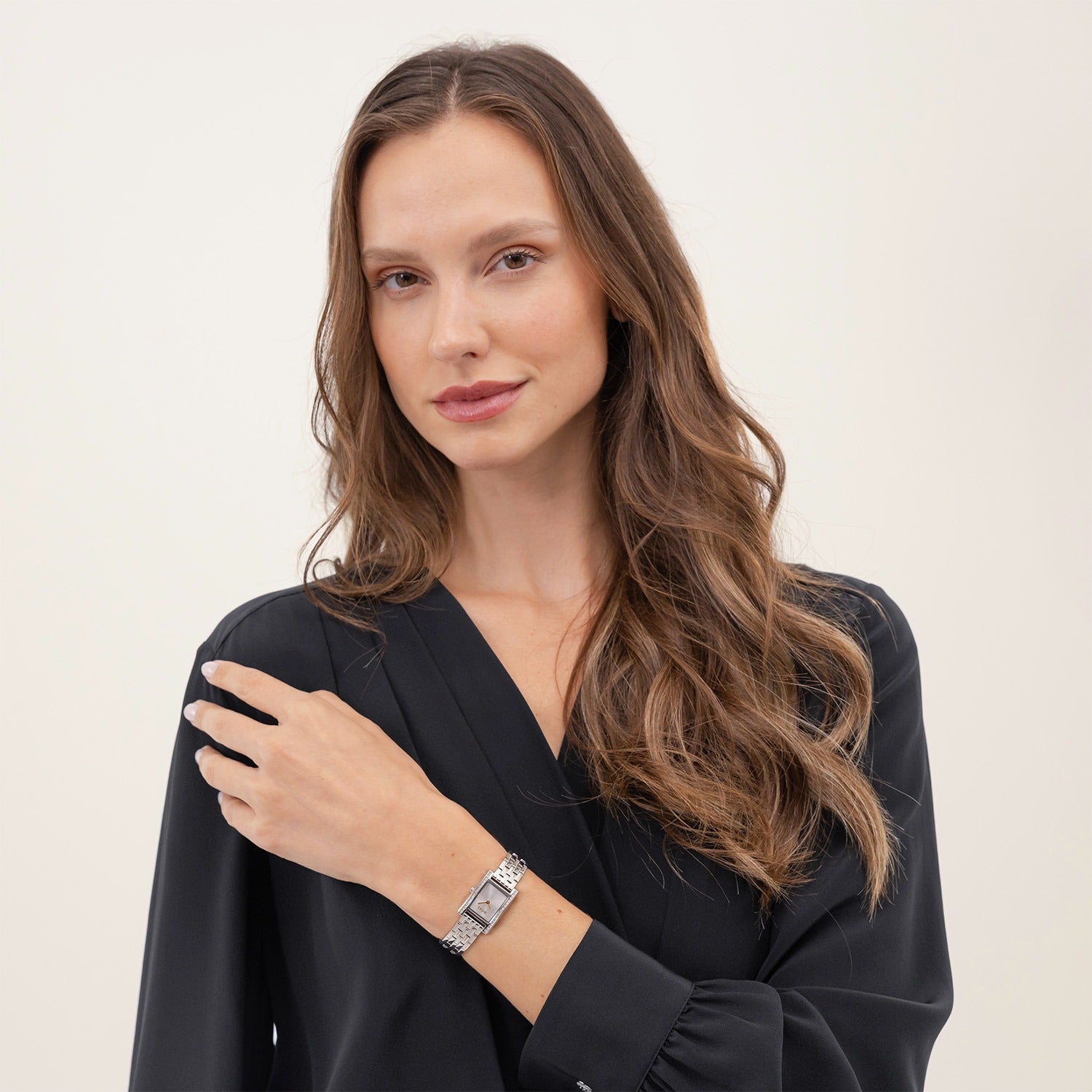 Damen-Armbanduhr am Handgelenk mit silberfarbenem Gliederarmband und rechteckigem Zifferblatt