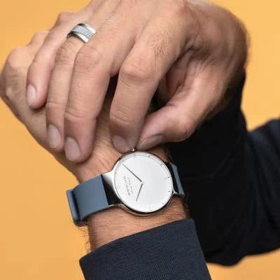 Herrenuhr am Handgelenk: blaues Silikonband, silbernes Gehäuse, weißes Zifferblatt