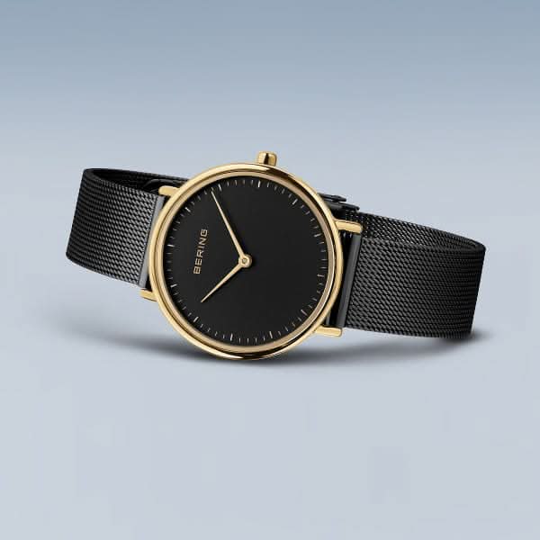 Montre Bering pour femme avec cadran noir, boîtier doré et bracelet milanais noir.