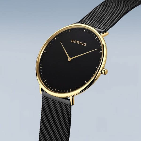 Montre pour femme avec cadran noir, boîtier doré, couronne, bracelet milanais noir.