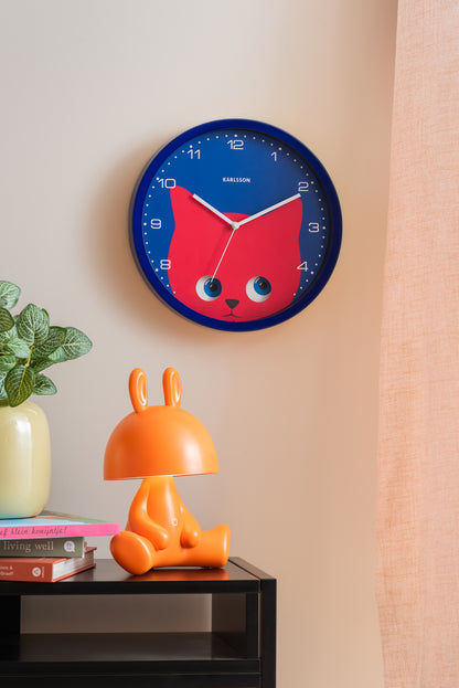Horloge murale bleu foncé sur un mur avec un motif de chat rouge, des yeux bleus et des chiffres