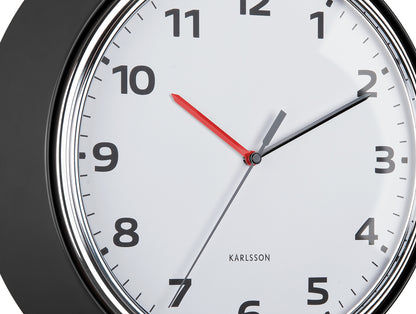 Gros plan d'une horloge murale : cadran blanc, aiguilles rouges et grises dans un cadre noir