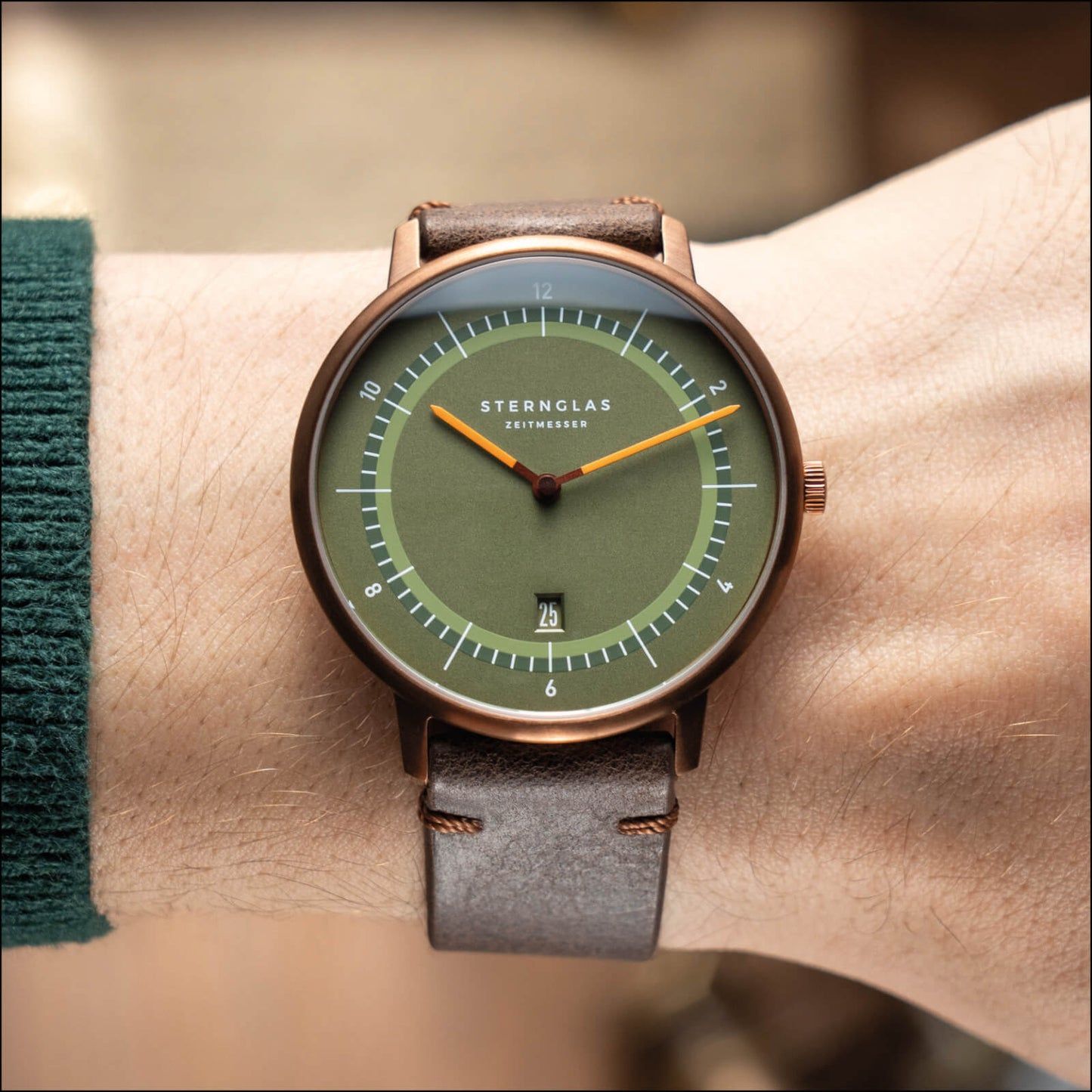 Montre pour homme au poignet : cadran vert, aiguilles orange, bracelet en cuir marron