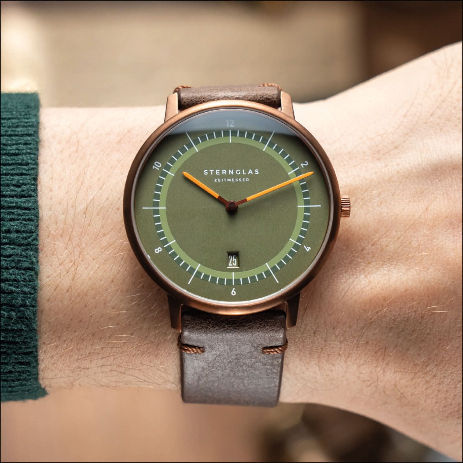 Montre unisexe au poignet : bracelet en cuir marron, cadran vert olive, boîtier en or rose