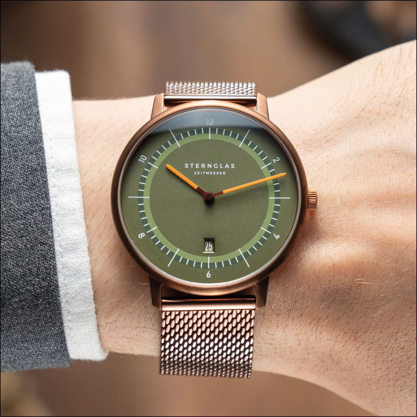 Montre unisexe avec cadran vert et bracelet métallique foncé, boîtier couleur cuivre.