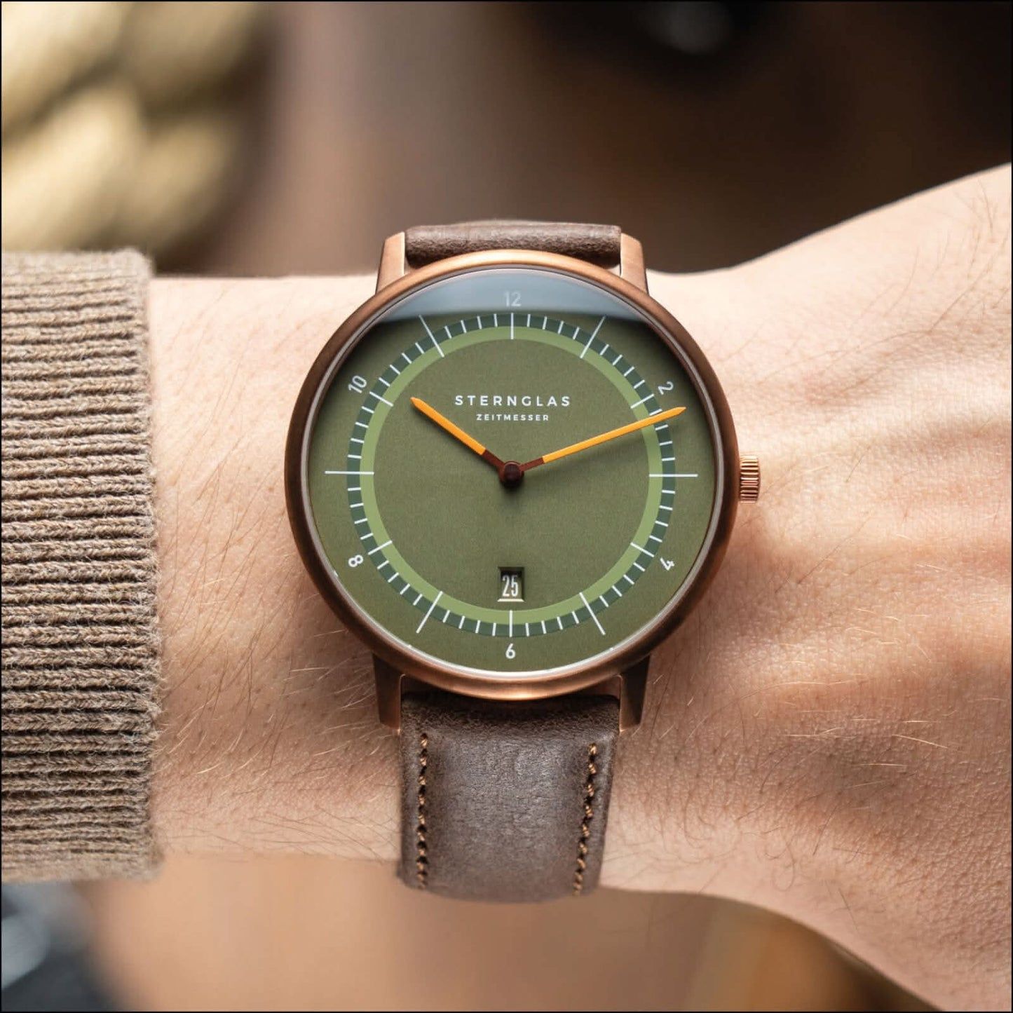 Montre unisexe avec cadran vert et bracelet en cuir gris-brun, boîtier couleur cuivre.