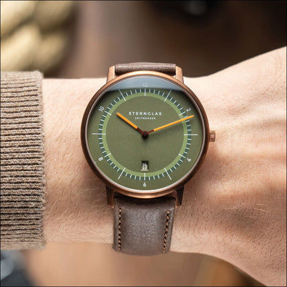 Montre unisexe avec cadran vert et bracelet en cuir gris-brun, boîtier couleur cuivre.